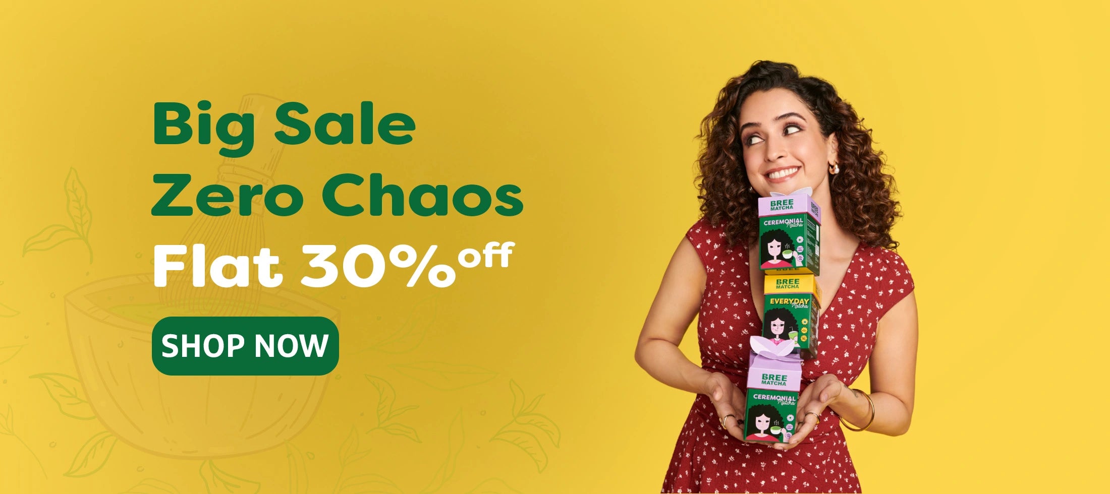 Smiling woman holding stacked boxes of Bree Matcha products against a yellow backdrop