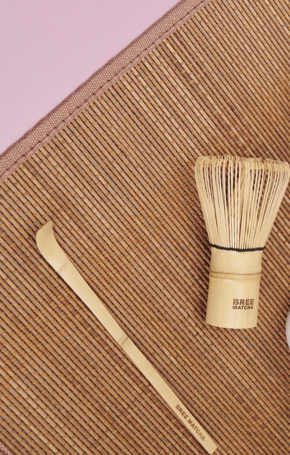 Matcha Bamboo whisk and scoop on a textured surface.